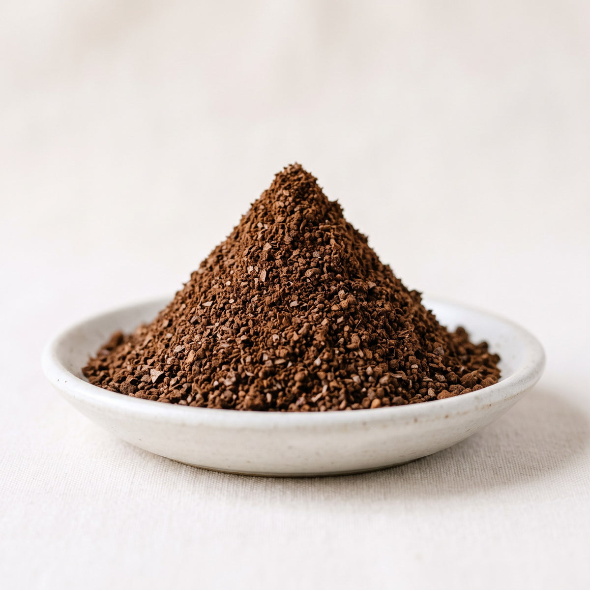 Conical mound of medium-coarse ground coffee in a white dish