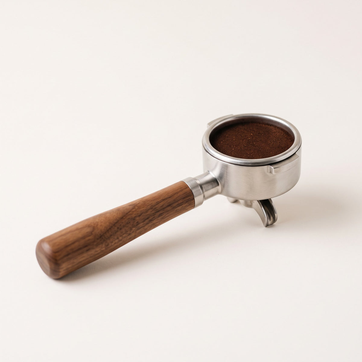 Bottomless portafilter holding a tamped puck of fine espresso grounds