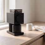 Electric burr coffee grinder on an oak kitchen counter in morning light