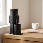 Black CF Wisdom portable burr coffee grinder with walnut lid on a kitchen counter
