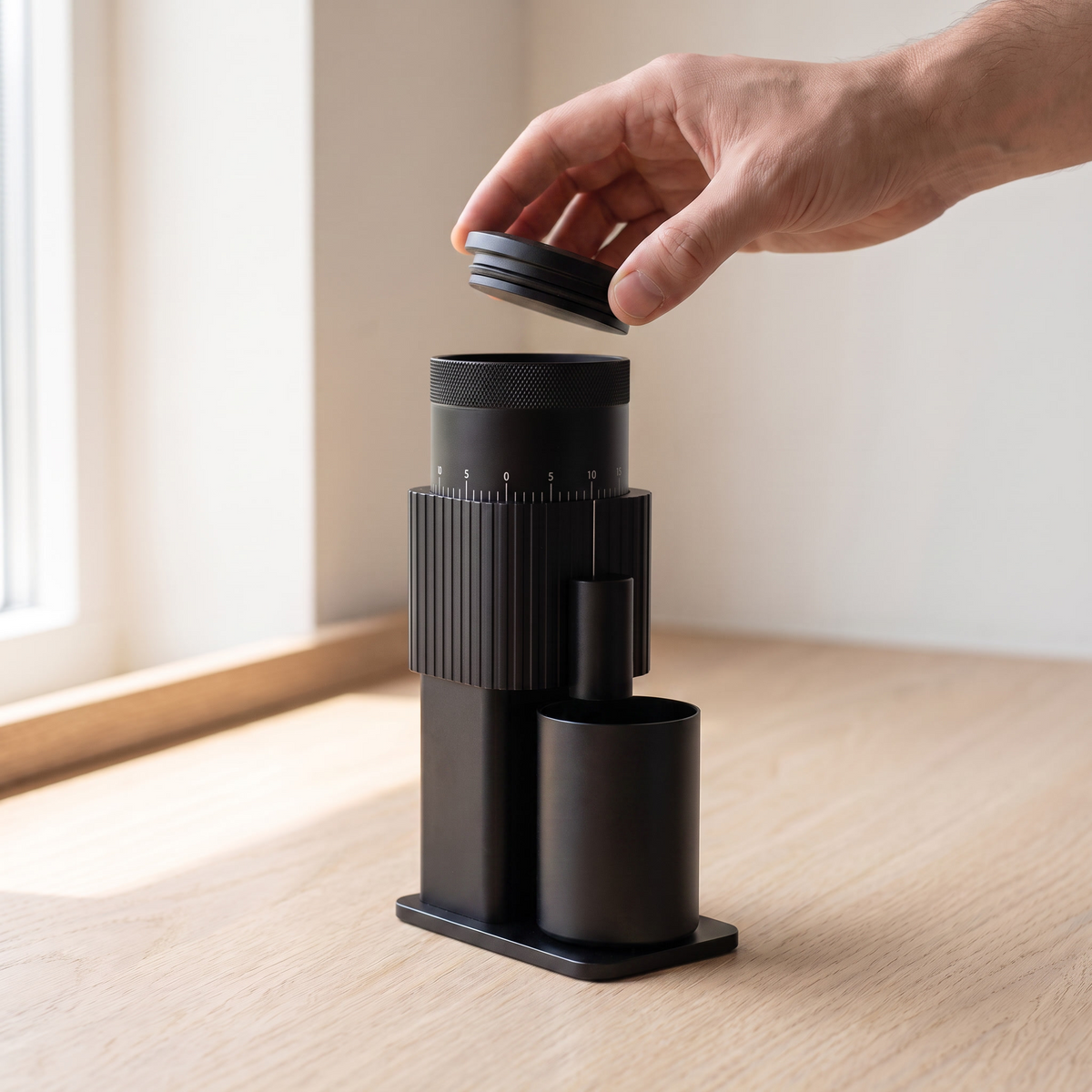 Hand lifting the black lid of an all black CF Wisdom portable grinder