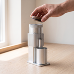 Hand lifting the walnut lid of a silver CF Wisdom portable grinder