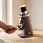 DF54 grey coffee grinder with a portafilter held under the chute