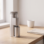 Silver SIMELO Alien portable grinder on a wooden counter beside a cup